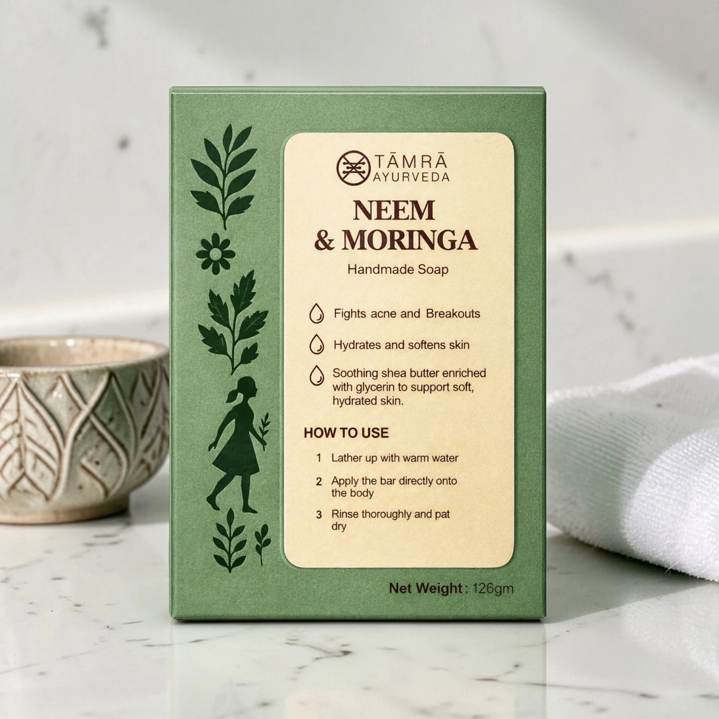 Támra Ayurveda Neem & Moringa soap packaging on a marble surface with a white towel and ceramic bowl.