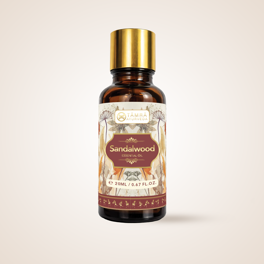 Tamra Ayurveda essential oil bottle with gold cap and decorative label on a beige background