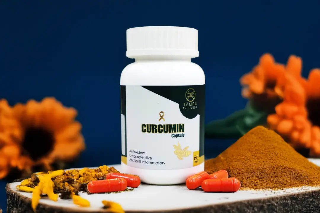 Curcumin supplement bottle with turmeric powder and flowers on a dark background