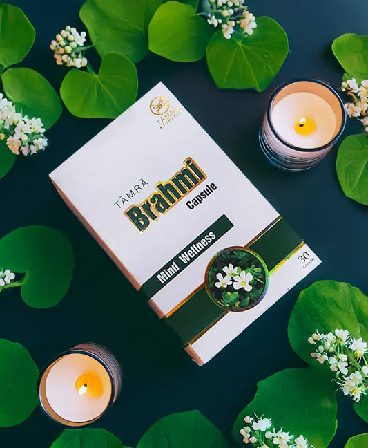 Box of Tamra Brahmi Capsules with candles and leaves on a dark background
