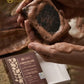 Chocolate soap held in hands with Tama Ayurveda branding in the background