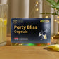 Box of 'Tamra Party Bliss Capsule' on a wooden surface with a glass of yellow liquid and lemon slices.