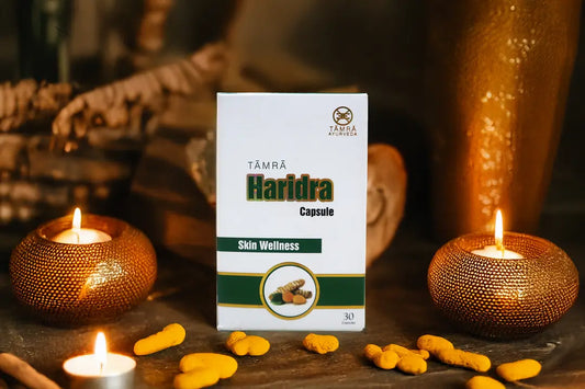 TAMRA Haridra Capsule packaging with capsules on a wooden surface with candles