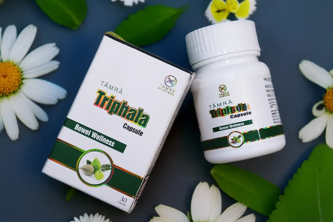 TAMRA Triphala Capsule packaging and bottle on a dark background with flowers