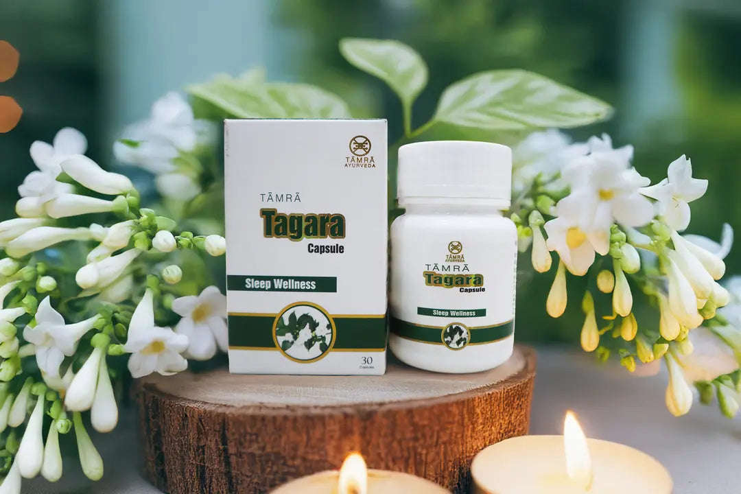 Tamra Tagara Capsules packaging and bottle on a wooden stand with flowers and candles in the background