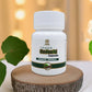 Bottle of Tamra Guduchi Capsules on a wooden block with green leaves in the background