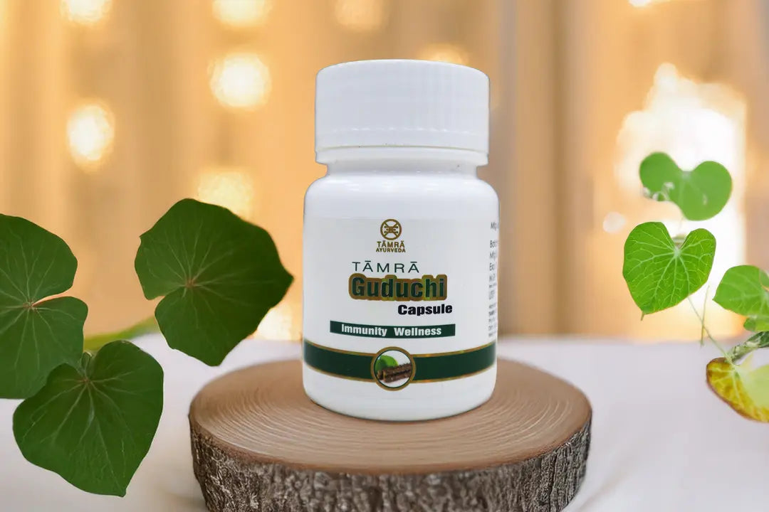 Bottle of Tamra Guduchi Capsules on a wooden block with green leaves in the background