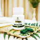 White bottle labeled 'TAMRA Arjuna' on a decorative tray with green capsules.