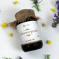 Jar of Tamra Chyawanprash with burlap lid on a white background with herbs.