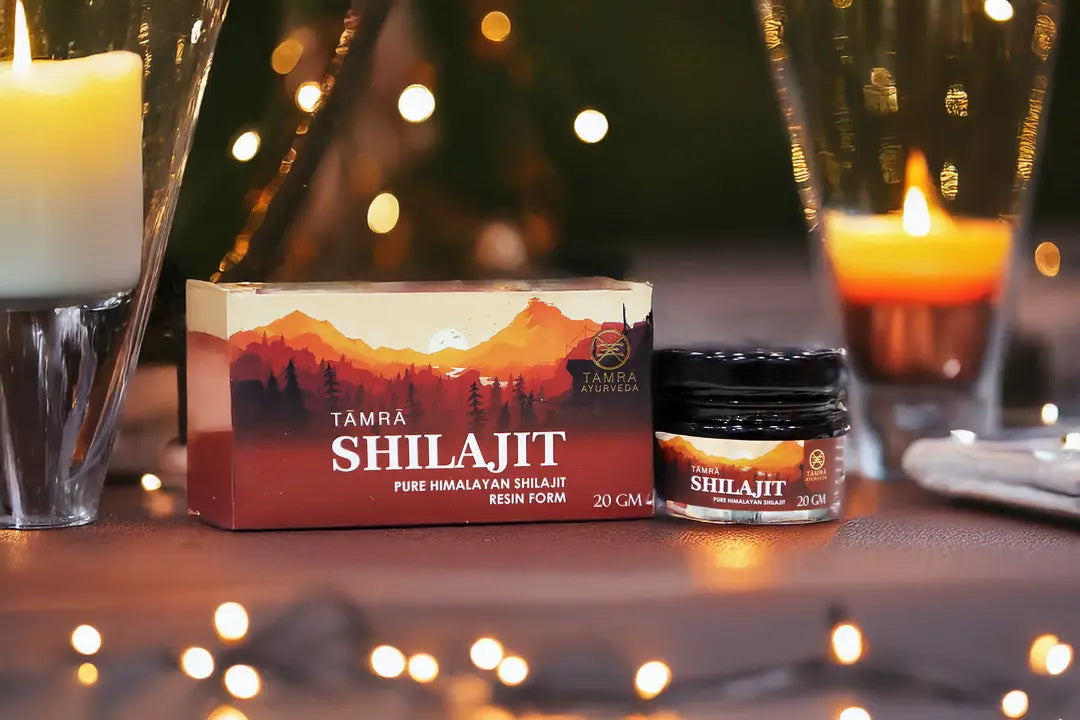 Tamra Ayurveda Shilajit packaging with candles and a blurred background of lights