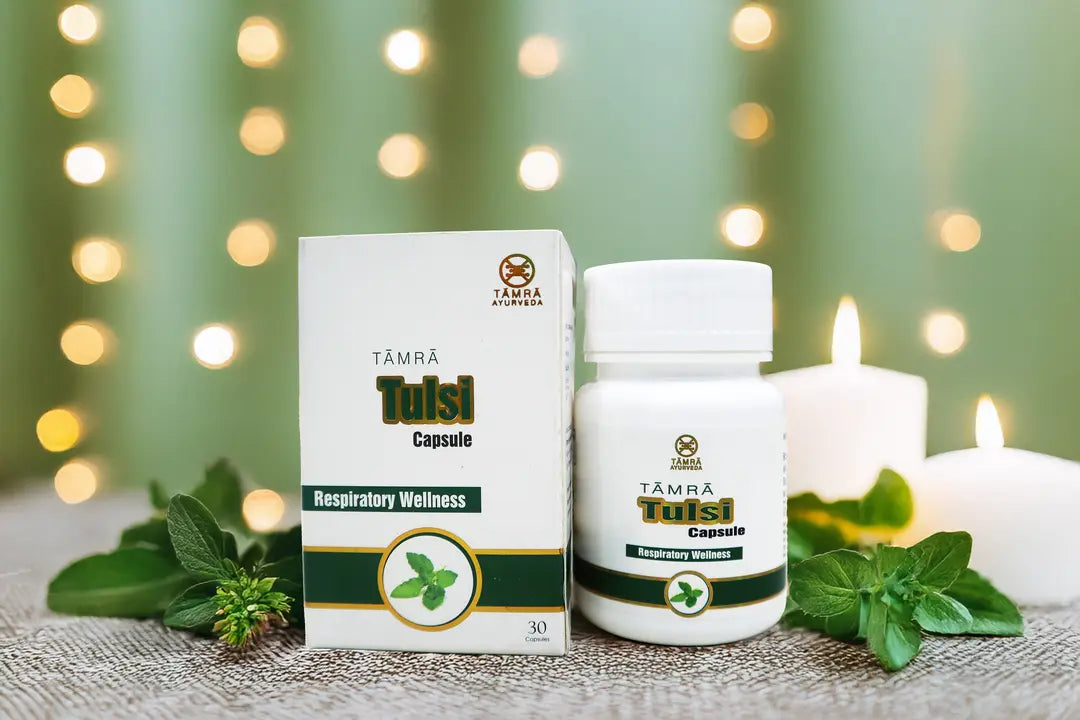 Tamra Tulsi capsules and packaging on a table with candles and greenery.