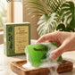 Green soap bar with foam on a wooden dish, Tamra Ayurveda box in the background, with a hand holding the soap.