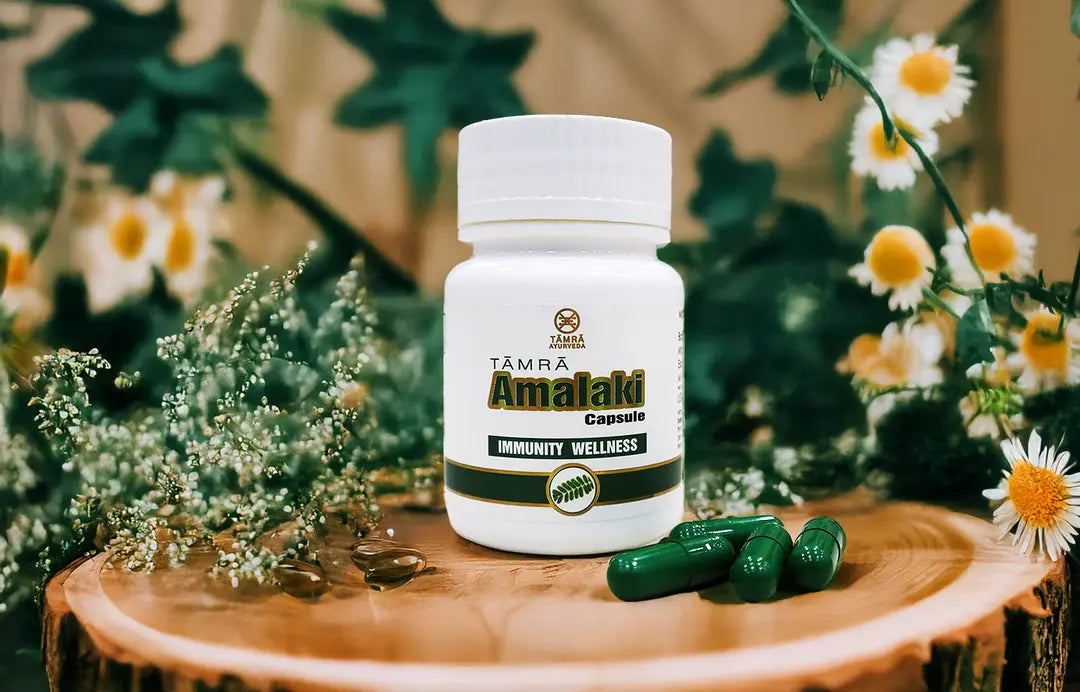 Tamra Ayurveda Amalaki capsule bottle on wood with green capsules