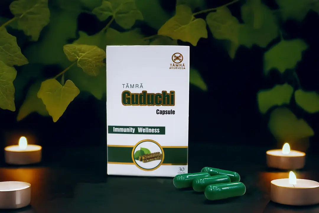 Tamra Guduchi capsule packaging with capsules on a dark background with candles and leaves.