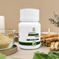 Tamra Ashwagandha capsule bottle on a table with ashwagandha roots and leaves.