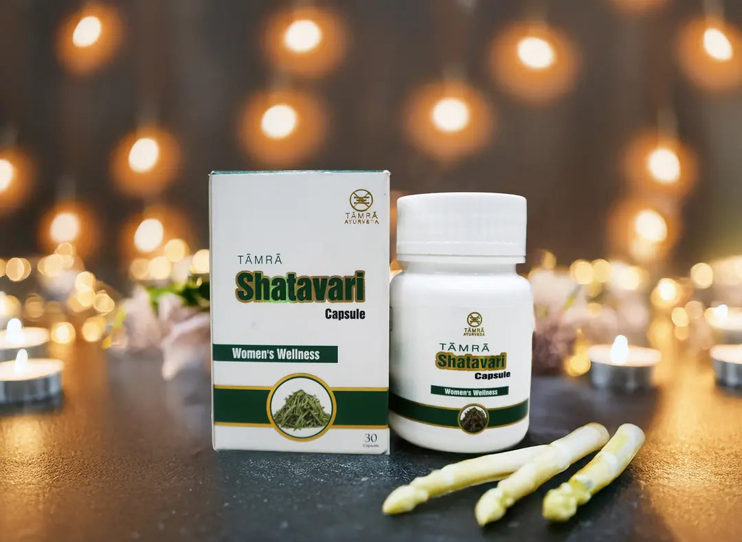 Tamra Shatavari capsules and packaging on a dark surface with blurred lights in the background