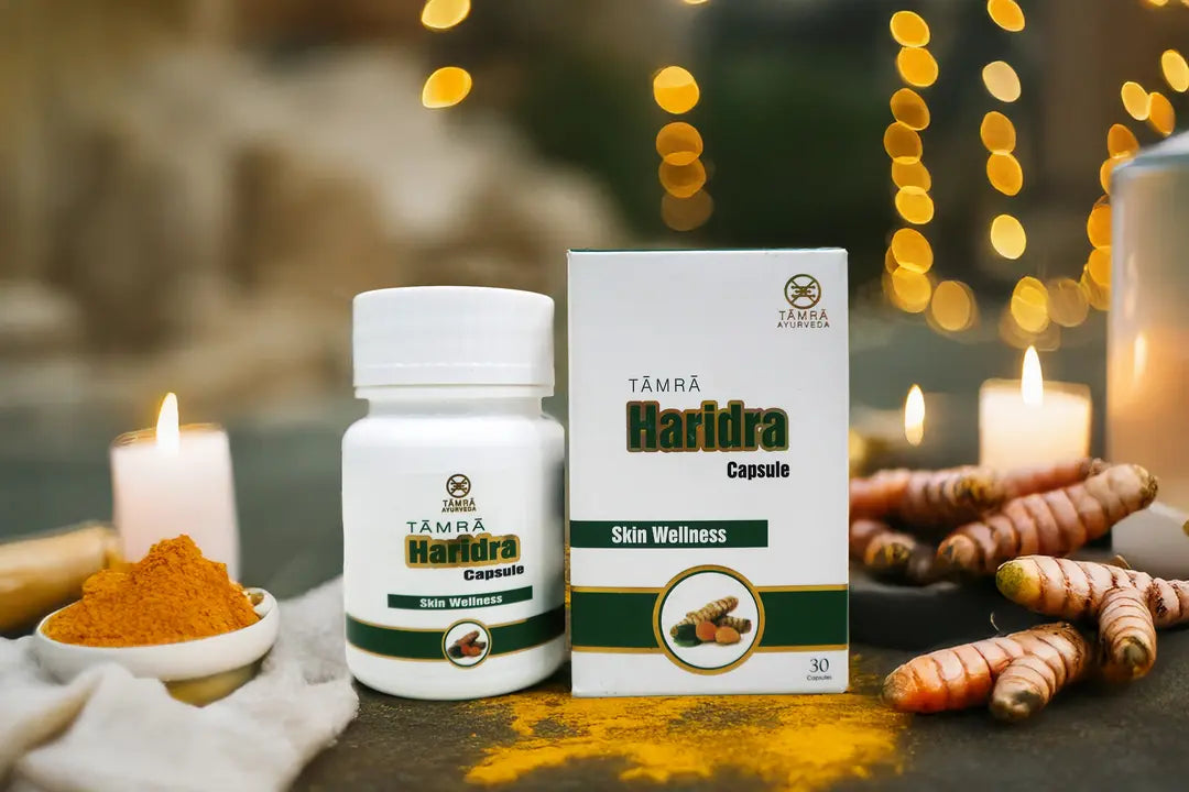 Tamra Ayurveda Haridra capsule bottle and packaging on a table with turmeric and candles.